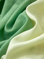 Vue rapprochée d'un tissu lisse dans des tons dégradés allant du vert clair au vert foncé, mettant en valeur une surface douce et texturée pour un Ensemble Robes et Chemisiers.